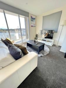 a living room with a white couch and a flat screen tv at Spacious & High in the Skyplaza - 1bd 1bth Apt in Phillip