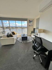 a living room with a couch and a desk and chair at Spacious & High in the Skyplaza - 1bd 1bth Apt in Phillip