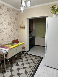 uma cozinha com uma mesa e um frigorífico branco em Двухкомнатная квартира em Shymkent