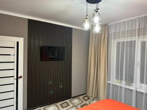 1 dormitorio con 1 cama y TV en la pared en Двухкомнатная квартира en Shymkent