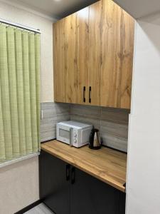 una cocina con encimera, microondas y armarios de madera. en Двухкомнатная квартира en Shymkent