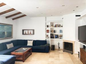 uma sala de estar com um sofá azul e uma televisão em Casa ChillOut a 6km de Sevilla Piscina comunitaria em Valencina de la Concepción