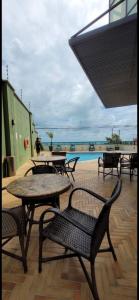 patio ze stołami i krzesłami oraz basenem w obiekcie Natal Plaza 604-Ponta Negra w mieście Natal