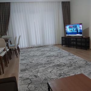 sala de estar con TV, mesa y sillas en شقة بمنتجع مياتيرمال, en Kaplıca
