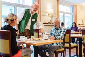 a man standing in a restaurant with two people sitting at a table at Gesundheits- & Wellness Resort Oberzeiring in Oberzeiring