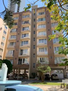 un gran edificio de apartamentos con una fuente frente a él en Apartamento Ilhas do Sul, en Balneário Camboriú