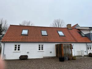 uma casa branca com um telhado vermelho em Farmens Gæstehus em Svebølle