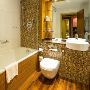 ein Badezimmer mit einer Badewanne, einem WC und einem Waschbecken in der Unterkunft Ashford International Hotel & Spa in Ashford