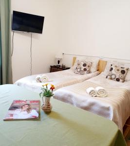 a hotel room with two beds with a magazine and flowers at Sunhome Stepanavan Guest House in Stepʼanavan