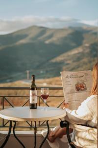 a woman sitting at a table with a bottle of wine and a glass at Anerada Hotel in Kalavrita