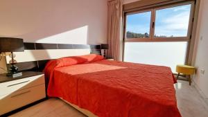 a bedroom with a red bed and a window at Large and sunny all-day balcony with stunning sea views in Benidorm