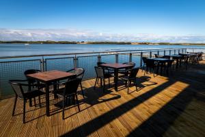 - une rangée de tables et de chaises sur une terrasse donnant sur l'eau dans l'établissement The Lake House, à Liverpool