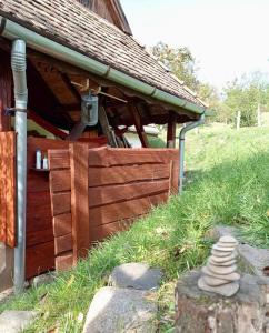 a wooden building with a porch and a stone stack at Nature Lodge Csesztve in Csesztve