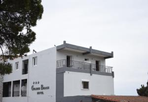 um edifício branco com uma varanda em Golden Beach Hotel em Metamorfosi