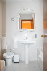 a white bathroom with a sink and a toilet at Hostal Los Valles in Bielsa