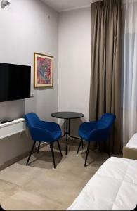 a hotel room with a table and two blue chairs at Avio Suite in Naples +28 photos