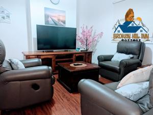 uma sala de estar com sofás e uma televisão de ecrã plano em Broken Hill Inn Cottage em Broken Hill