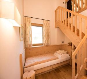 Ce lit se trouve dans un dortoir doté d'un escalier en bois. dans l'établissement Haus Sonnegg Panoramasuite, à Laion
