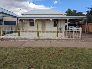 una cerca blanca frente a una casa en Broken Hill Inn Cottage, en Broken Hill