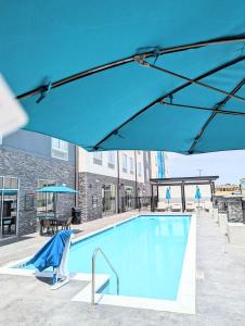 a pool with a blue umbrella and tables and chairs at Candlewood Suites - Tulsa Hills - Jenks, an IHG Hotel in Jenks