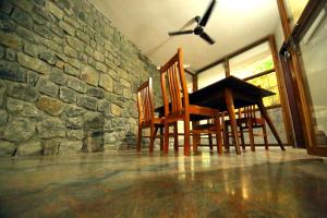 a table and chairs in a room with a stone wall at AYURGREEN HERITAGE in Kattappana
