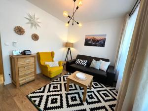 a living room with a black couch and a yellow chair at Apartmány Bobulky in Tatranská Lomnica
