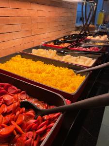 um buffet de diferentes tipos de alimentos em bandejas em Saint Patrick Grand Hotel em Maceió