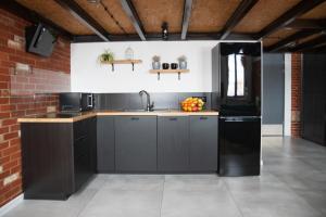 a kitchen with black cabinets and a sink at RedCity LOFT 303 in Żyrardów