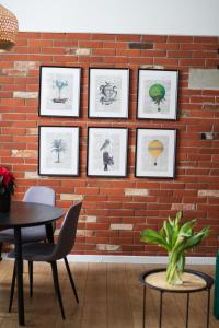 a brick wall with framed pictures and a table and chairs at RedCity LOFT 303 in Żyrardów
