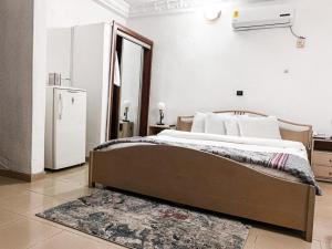 1 dormitorio con 1 cama grande y nevera en Hill View Hotel West Airport en Accra