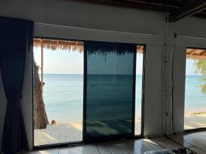 Habitación con puertas correderas de cristal y vistas al océano. en Haad Chao Phao Resort en Haad Chao Phao