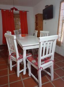 mesa de comedor blanca con 4 sillas blancas en Cabañas Espinillos del Lago in 