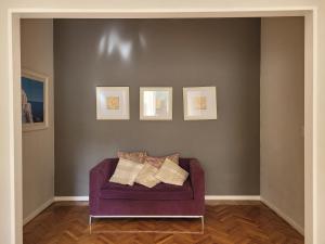 un sofá púrpura sentado en una sala de estar con pinturas en Plaza de Mayo a la vuelta en Buenos Aires
