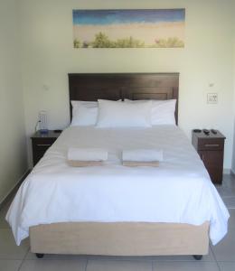 a bedroom with a large white bed with two towels on it at Pro Moni's Guesthouse in Muizenberg