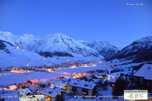 una città nella neve di notte con una montagna di Casa Longa a Livigno