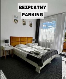 sypialnia z łóżkiem i znakiem, który czyta parking kierowniczy w obiekcie Apartamenty Planeta Mielno w mieście Mielno