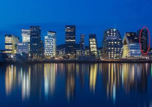 a city skyline with the ferris wheel in the water at Spacious modern 2BR apartment at Central OSLO BARCODE in Oslo