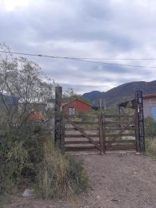 ein Holztor auf einem Feld mit einem roten Haus in der Unterkunft Casa Cerro Arco in Mendoza