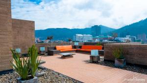un patio en la azotea con muebles de color naranja y vistas a la ciudad en FH - Stunning apartment in Chico, en Bogotá