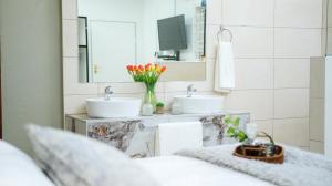 Baño con 2 lavabos y espejo en Jose Guesthouse, en Kempton Park