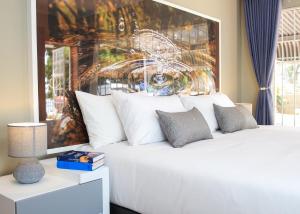 1 dormitorio con 1 cama blanca y una gran pintura en Jose Guesthouse, en Kempton Park