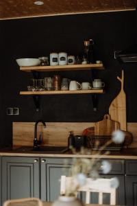a kitchen with black walls and a sink and shelves at Szumilove Domki z saunami w Bieszczadach in Baligród