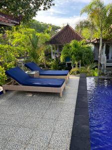 a pool with blue lounge chairs next to a house at The Ocean Sunset Villas Ceningan in Nusa Lembongan