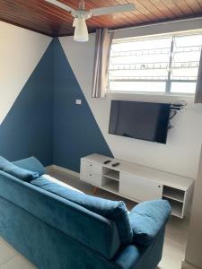 a living room with a blue couch and a tv at Suite 237 in Itanhaém