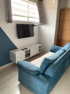 sala de estar con sofá azul y TV en Suite 237 en Itanhaém