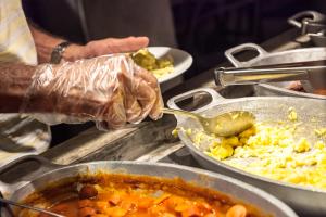 a person with a spoon in a pot of food at Mar Ipanema Hotel in Rio de Janeiro