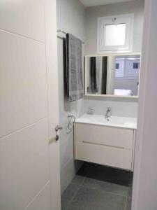 a white bathroom with a sink and a mirror at 3 bdrm Cityview Apt with Pool, Gym & Children Playground in Accra