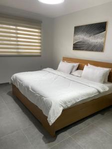 una camera da letto con un grande letto con lenzuola e cuscini bianchi di 3 bdrm Cityview Apt with Pool, Gym & Children Playground a Accra