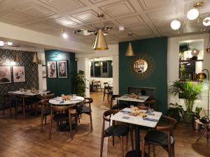 un ristorante con tavoli, sedie e pareti verdi di The Swan - A Colombo Edition Hotel a Ely