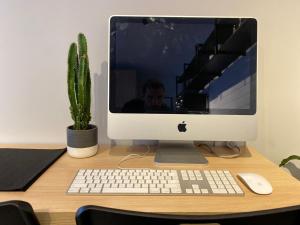 a computer monitor sitting on a desk with a cactus at Novo Studio Garden in Sao Paulo